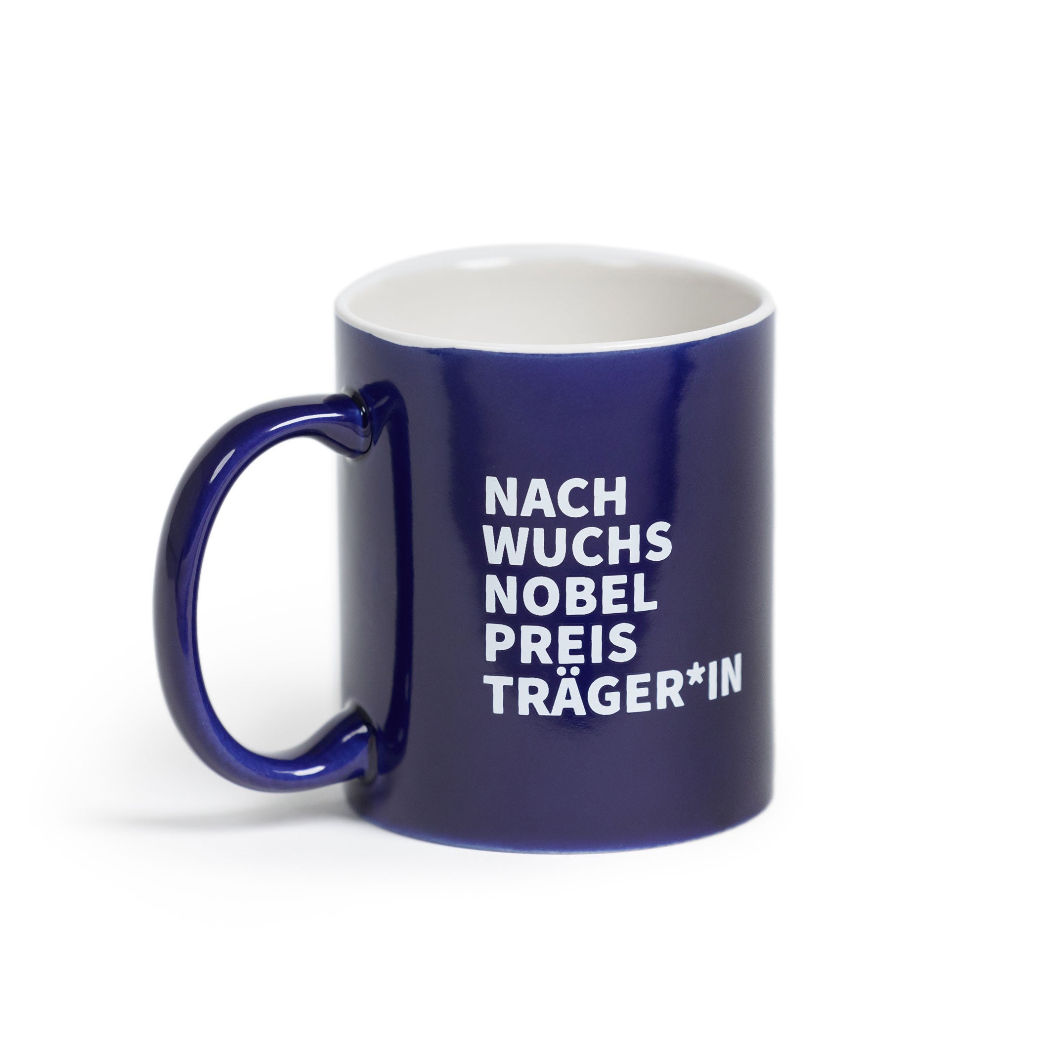 Dunkelblaue Keramiktasse mit weißem Innenraum und Henkel, bedruckt mit dem weißen Schriftzug „NACH WUCHS NOBEL PREIS TRÄGER*IN“, freigestellt vor hellem Hintergrund.
