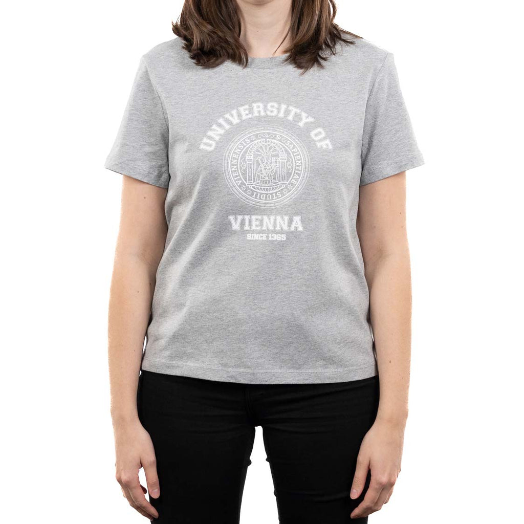 Frontansicht einer weiblichen Person im grauen T‑Shirt. Auf der Brust ein großer weißer Collegedruck mit Siegel: „UNIVERSITÄT WIEN“ und darunter „SEIT 1365“.